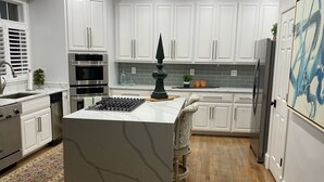 A modern kitchen with white cabinetry, a central island, built-in appliances, and a patterned floor. - Great Get Away Home  (Henrico)