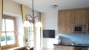 A kitchen with wooden cabinets, a microwave, and a dining area with a table and chairs.
