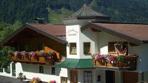 A traditional Alpine-style building with a sign 'Landhaus GRUBER' and a balcony with flower boxes.