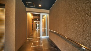 A hallway with a textured wall, a metal handrail, and a door leading to another room. - Rakuten STAY Hakata Gion (Fukuoka)