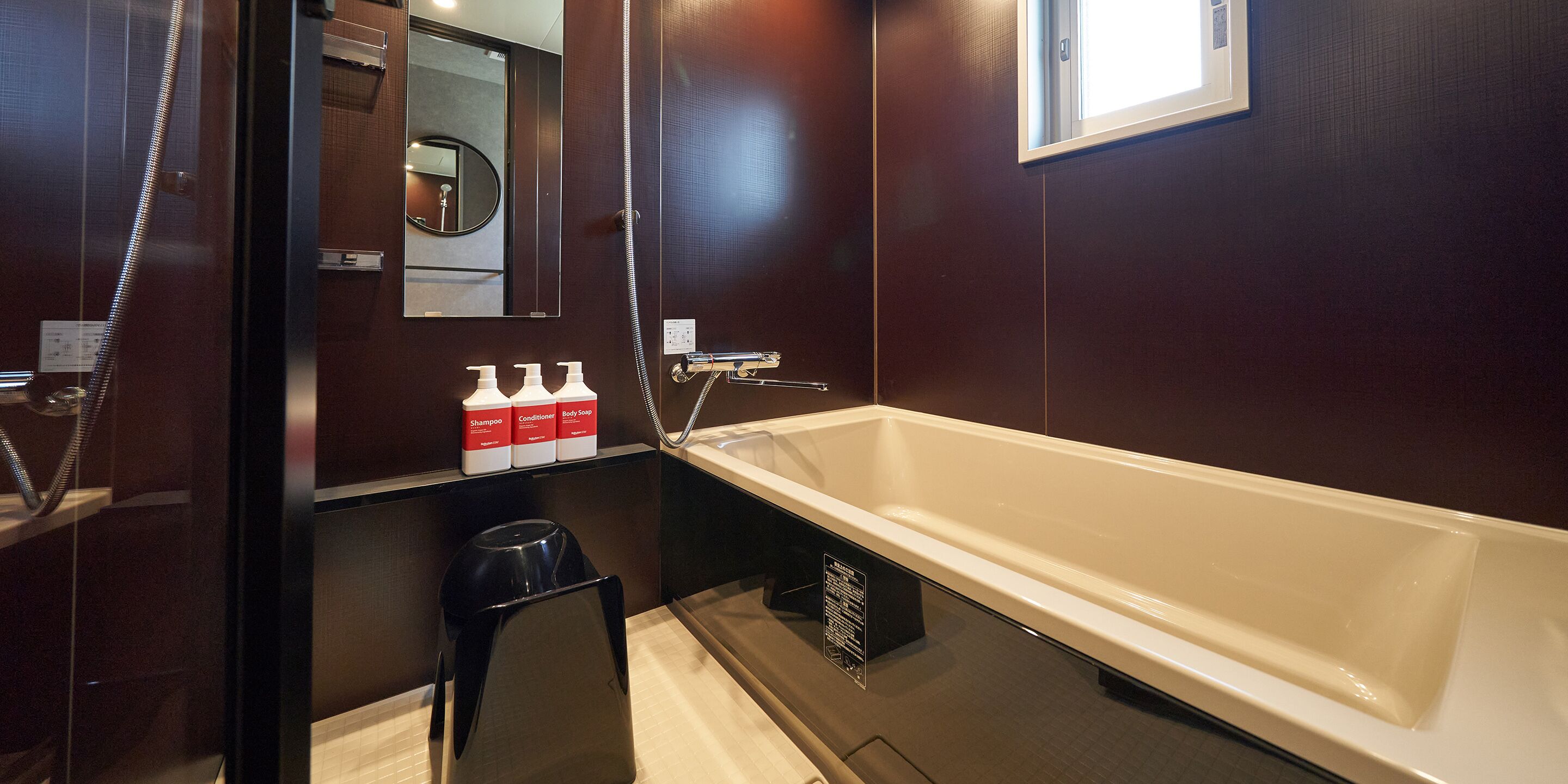 A modern bathroom with a large bathtub, a mirror, and toiletries on a shelf.