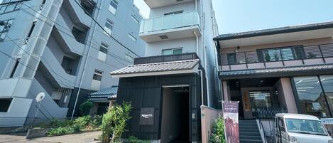 A modern building with a sign for Fukuoka City, a parking area, and a vehicle parked outside.