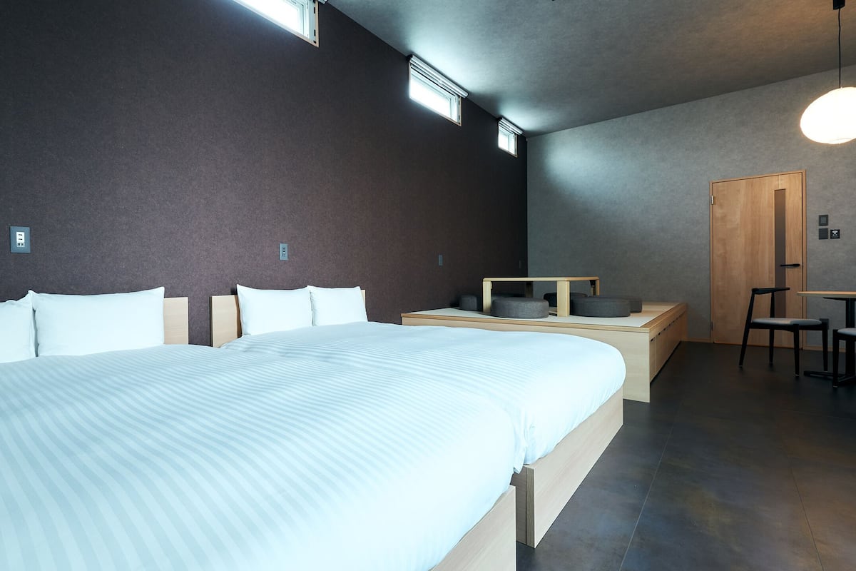 A modern hotel room with a large bed, a desk with a chair, and a small seating area.