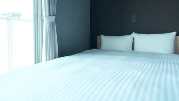 A neatly made bed with white bedding and a wooden headboard in a room with a dark wall and a window with curtains.
