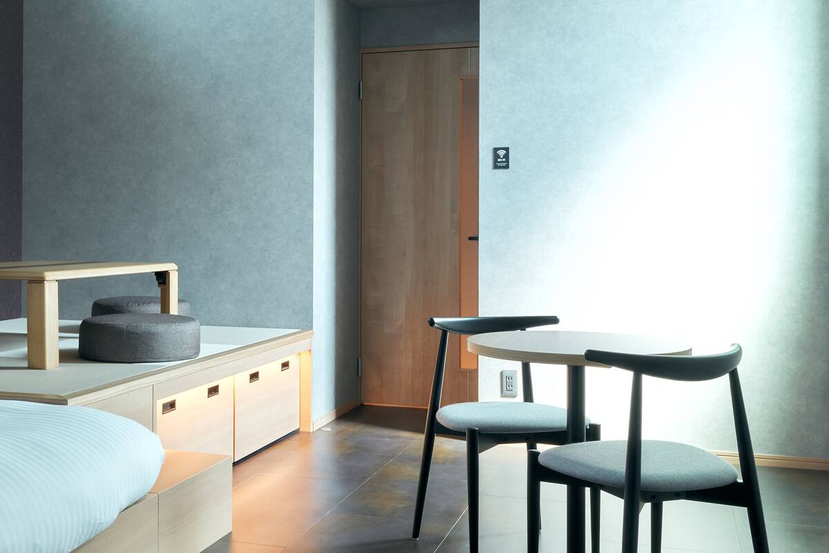 A modern bedroom with a bed, a small table, two chairs, and a wardrobe.