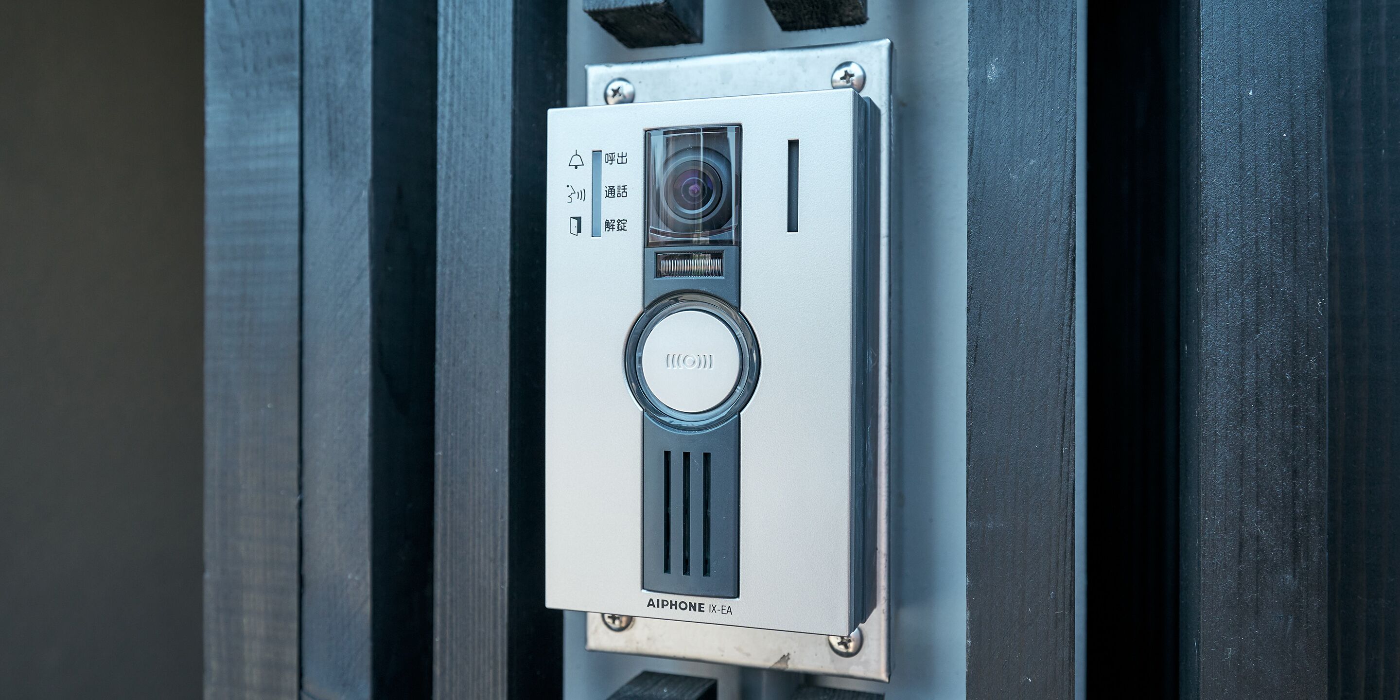 A security intercom system with a camera and a keypad, mounted on a metallic surface.