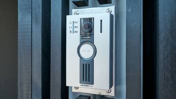 A security intercom system with a camera and a keypad, mounted on a metallic surface.