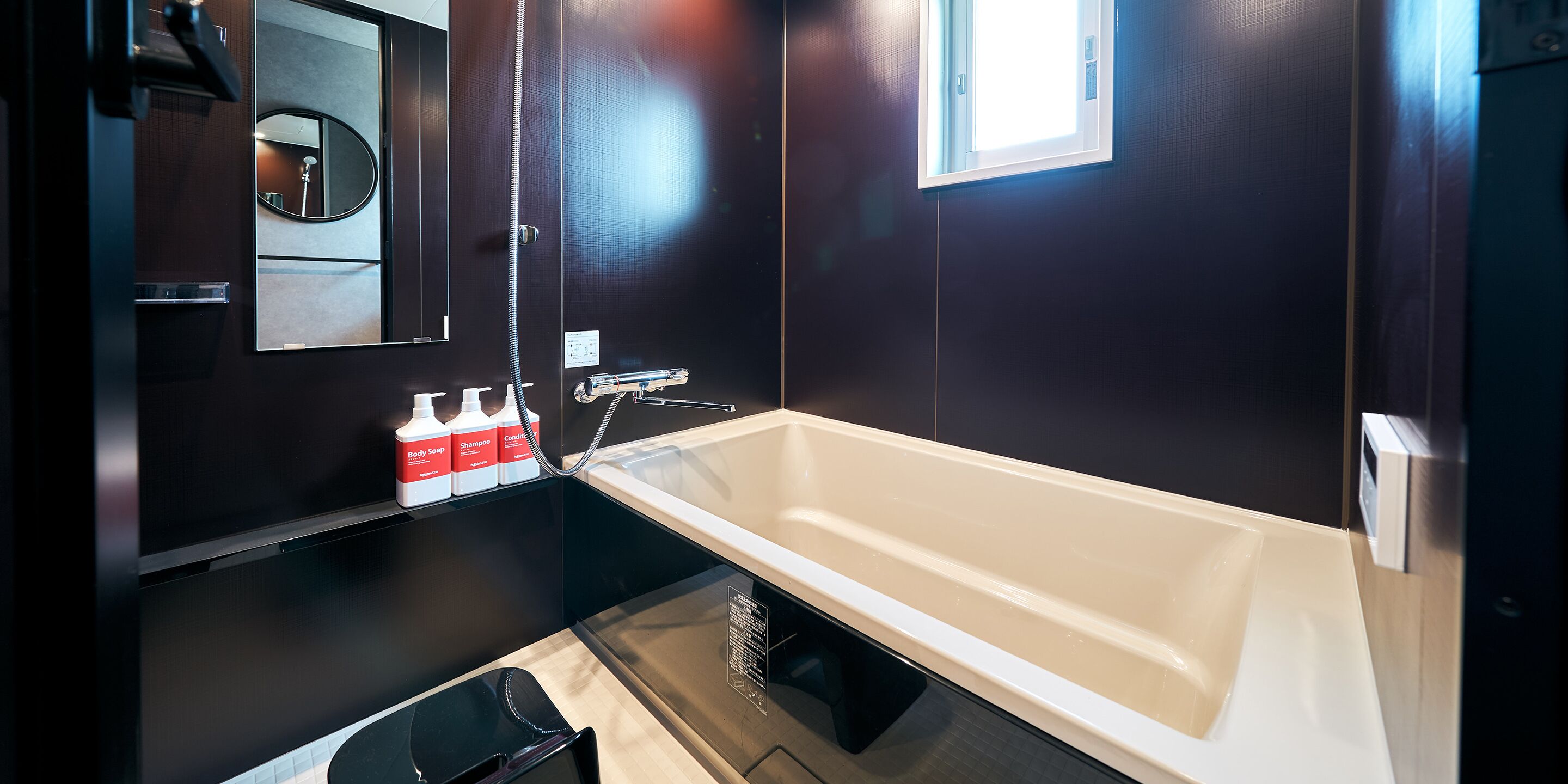 A modern bathroom with a large bathtub, a mirror, and a window.
