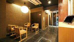 A reception area with a reception desk, three wooden chairs, a large round light fixture, and a tiled floor. - Rakuten STAY Hakata Gion (Fukuoka)