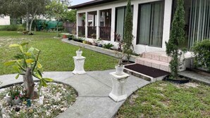 A modern house with a covered porch, a well-maintained lawn, and a small garden area with potted plants.