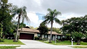 A single-story house with a garage, surrounded by palm trees and a well-maintained lawn.