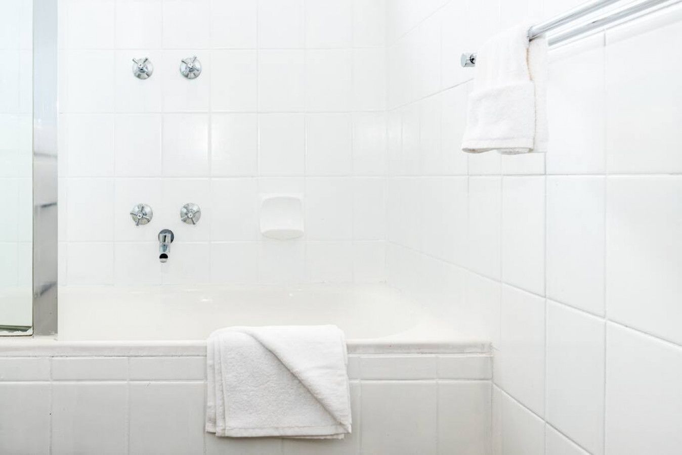 A bathroom with a bathtub, a towel rack, and a showerhead.