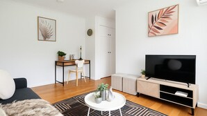 Ein modernes Wohnzimmer mit einer Couch, einem Couchtisch, einem Fernseher, einem Schreibtisch und einem Schrank.