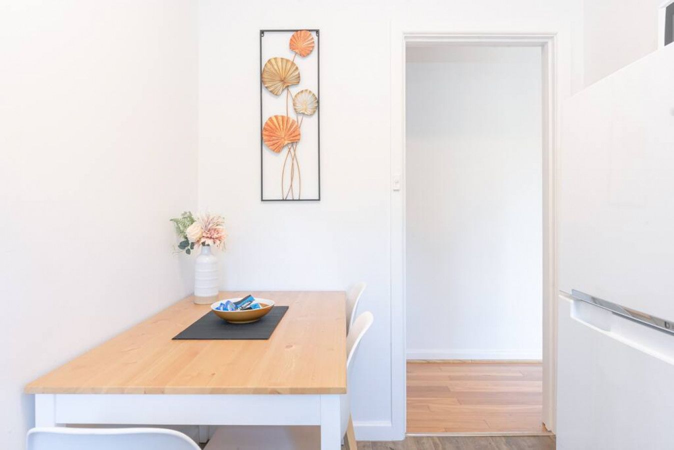 Ein kleiner Essbereich mit einem Holztisch, einer Blumenvase und einem Wandbild.