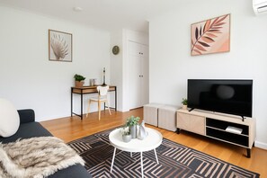 Un salon moderne comprenant un canapé, une table basse, un téléviseur, un bureau et un meuble.