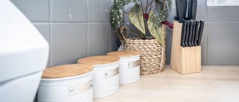 A kitchen with white storage bins, a woven basket with a plant, and a knife block.