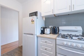 Una cocina compacta equipada con refrigerador, tostadora, hervidor y estufa.