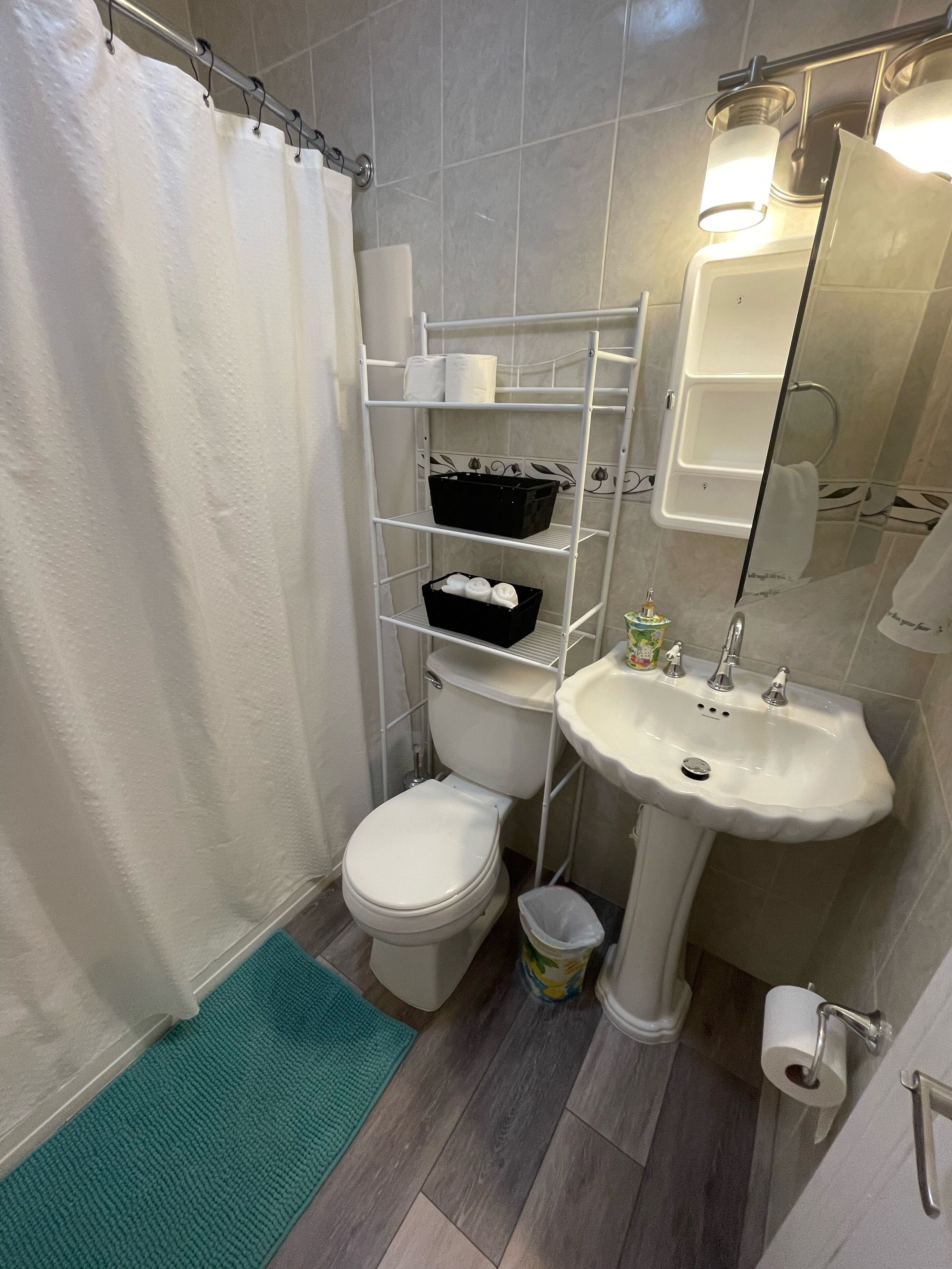 A bathroom with a toilet, sink, and shelves with toiletries.