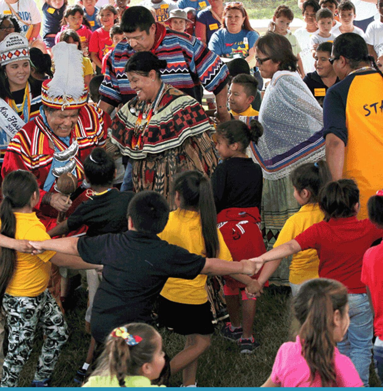 A group of people, including children, participating in a cultural event outdoors.