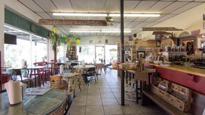 A cozy cafe with tables and chairs, a counter with various items, and a 'WELCOME FRIENDS' sign.