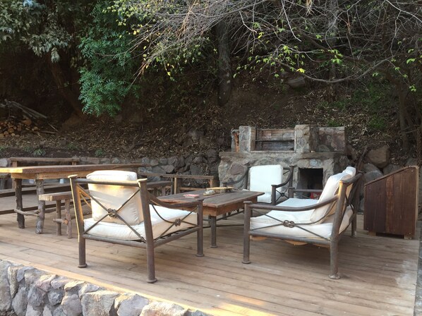 An outdoor patio with wooden furniture and a stone fireplace. - House on the way to Farellones (Santiago)