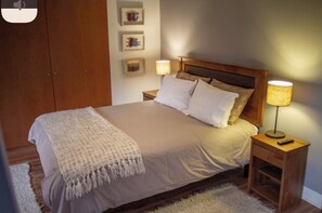 Cozy bedroom with a large bed, two nightstands, and a wooden wardrobe, featuring a comfortable sleeping environment.
