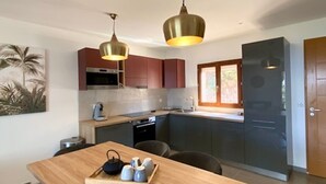 A modern kitchen with dark cabinets, a wooden dining table, and two pendant lights. - Residence La Listrella apt 4 (Monticello)