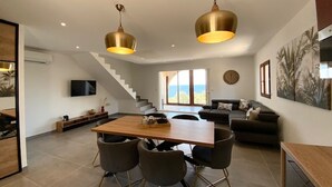 A spacious living area with a dining table, modern chairs, and a staircase leading to an upper floor. - Residence La Listrella apt 4 (Monticello)