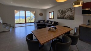 A spacious living area with a wooden dining table, black chairs, and a sofa with cushions. There are two pendant lights above the table. - Residence La Listrella apt 4 (Monticello)