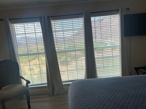 A room with a bed, a chair, and a window with blinds.