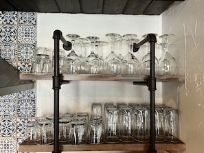 Un mueble con estantes que exhibe varios objetos de vidrio, como copas de vino y vasos.