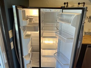 Un refrigerador con varios estantes y compartimentos, incluyendo un congelador en la parte superior.