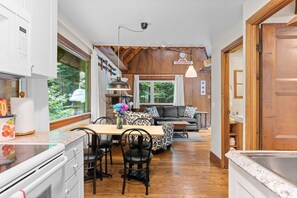 Una cocina con comedor, piso de madera y vista a zonas verdes.