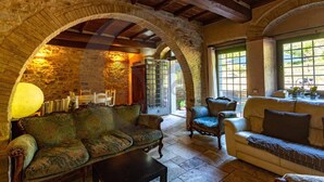 Un intérieur chaleureux avec une arche en pierre, un canapé vert recouvert de tissu, un canapé blanc et une chaise en bois.
