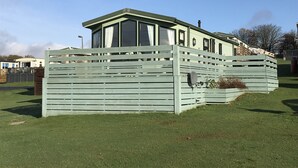 Ein eingeschossiges Haus mit Gründach, großen Fenstern und einem eingezäunten Garten.