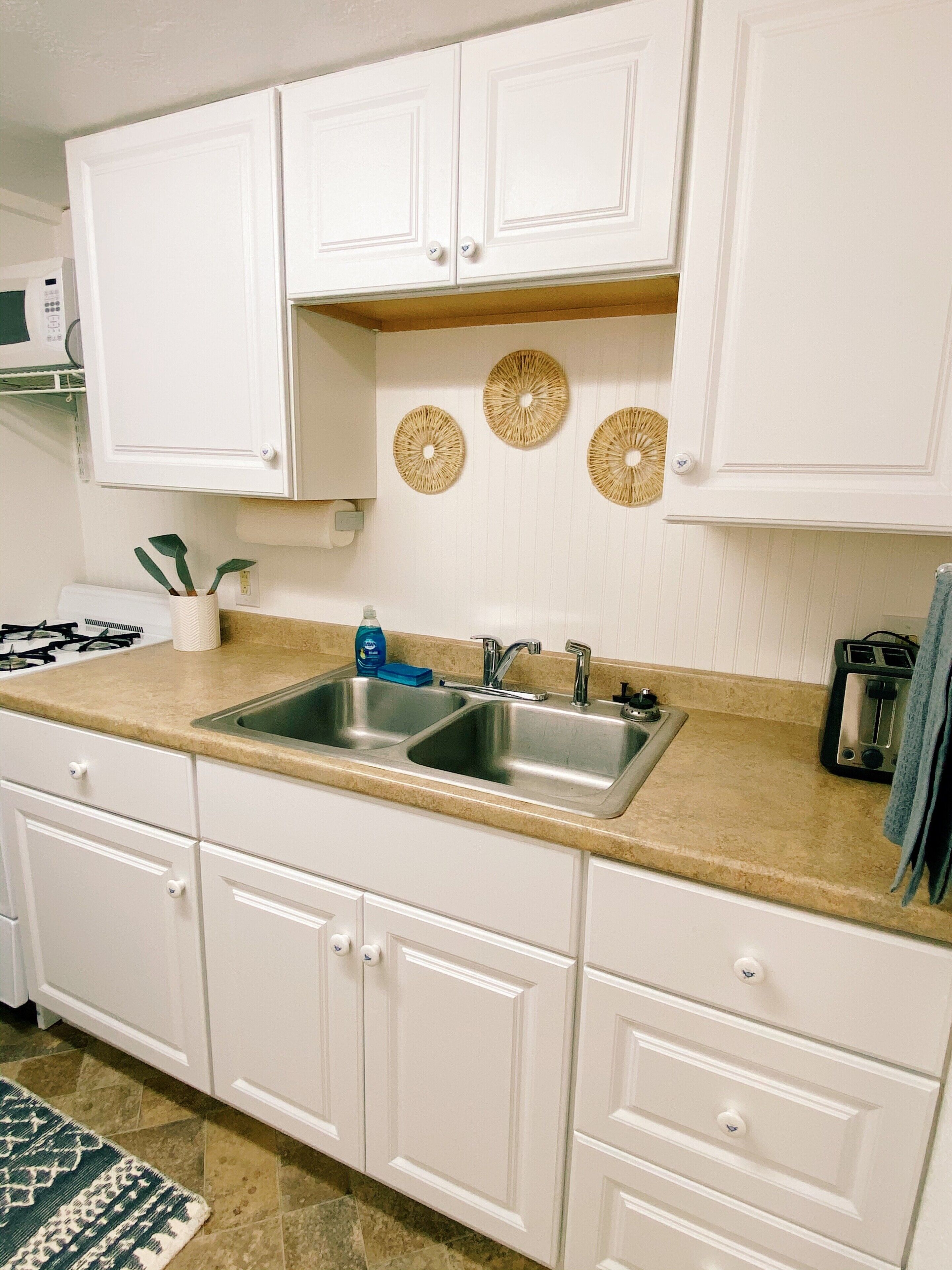 A kitchen with white cabinets, a double sink, and a countertop with a toaster.