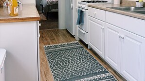 Une cuisine de taille réduite avec des meubles blancs, un réfrigérateur, une cuisinière et un four à micro-ondes.