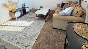 Un salon équipé d’un téléviseur à écran plat, d’un canapé, d’une table basse et d’un tapis à motifs.