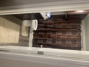 Bathroom with shower area, toilet, and bath mat.