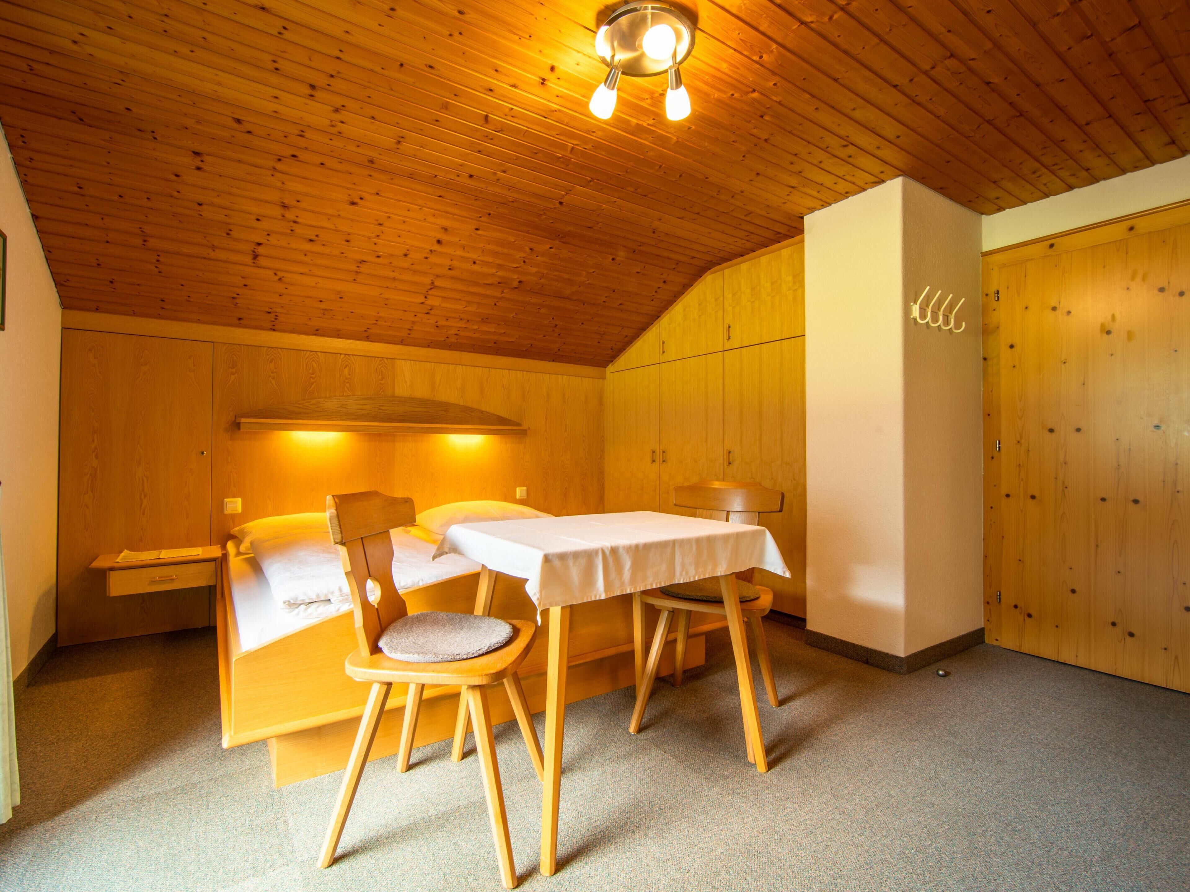 Una habitación acogedora con techo de madera, una cama, una mesa y sillas.