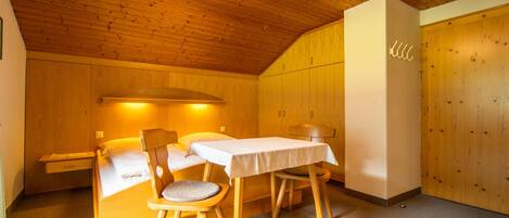 Una habitación acogedora con techo de madera, una cama, una mesa y sillas.