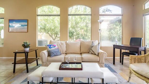 A living room with a beige sofa, a coffee table with a tray, a small table with a plant, and a chair. - Private home,2 King Beds, near Empire Polo, Tennis, Pools, Coachella, Horse Pk, (Indio)