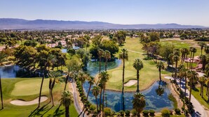 A golf course with a water feature, surrounded by palm trees and a clear sky. - Private home,2 King Beds, near Empire Polo, Tennis, Pools, Coachella, Horse Pk, (Indio)