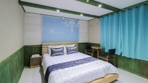 A neatly arranged bedroom with a bed, bedside tables, a small round table, and a chair. - Hotel The May (Busan)