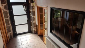 A hallway with a stone wall, a glass door, and a window. - House in Carladez with private sauna (Brommat)