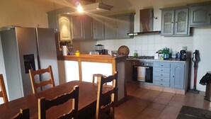 A kitchen with a dining table, chairs, cabinets, a refrigerator, an oven, and a coffee maker. - House in Carladez with private sauna (Brommat)