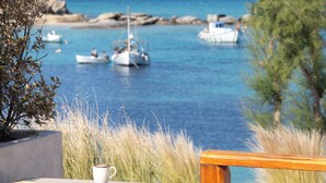 A table with a straw hat, a plate with food, and a cup, overlooking a marina with boats. - Avgoustos Suites - Adults only (Naxos)