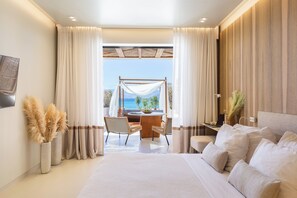 A modern bedroom with a large bed, a desk, and a view of the sea. - Avgoustos Suites - Adults only (Naxos)