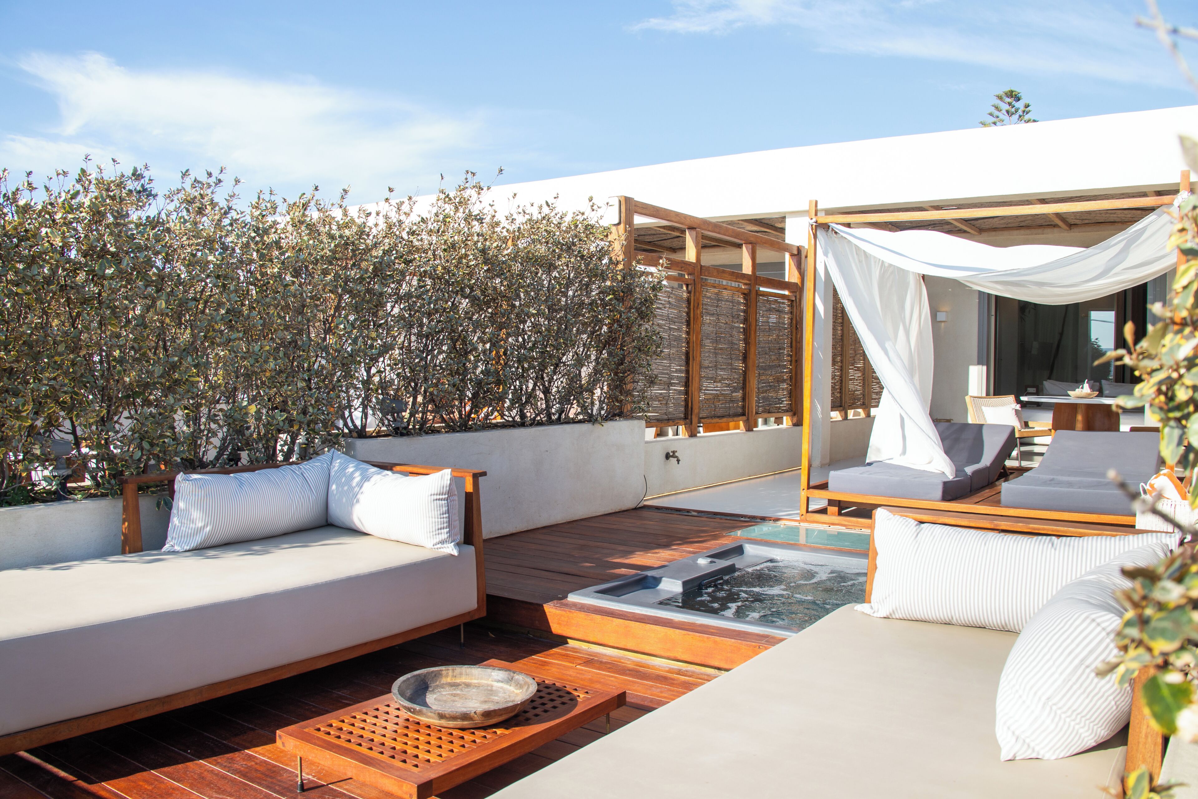 A rooftop terrace with a wooden deck, a white outdoor sofa, and a canopy.