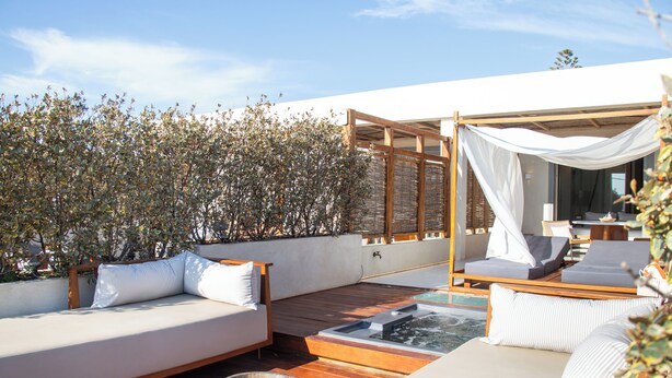 A rooftop terrace with a wooden deck, a white outdoor sofa, and a canopy. - Avgoustos Suites - Adults only (Naxos)